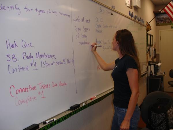 Science teacher Melissa McCullough writes the daily agenda on the board for her class.