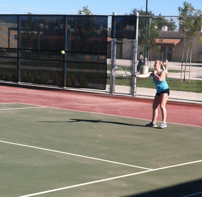 A member of the girls tennis team volleys with a teammate during practice.