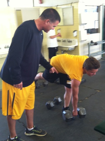 Chuck Selna teaches a student how to properly lift a weight.