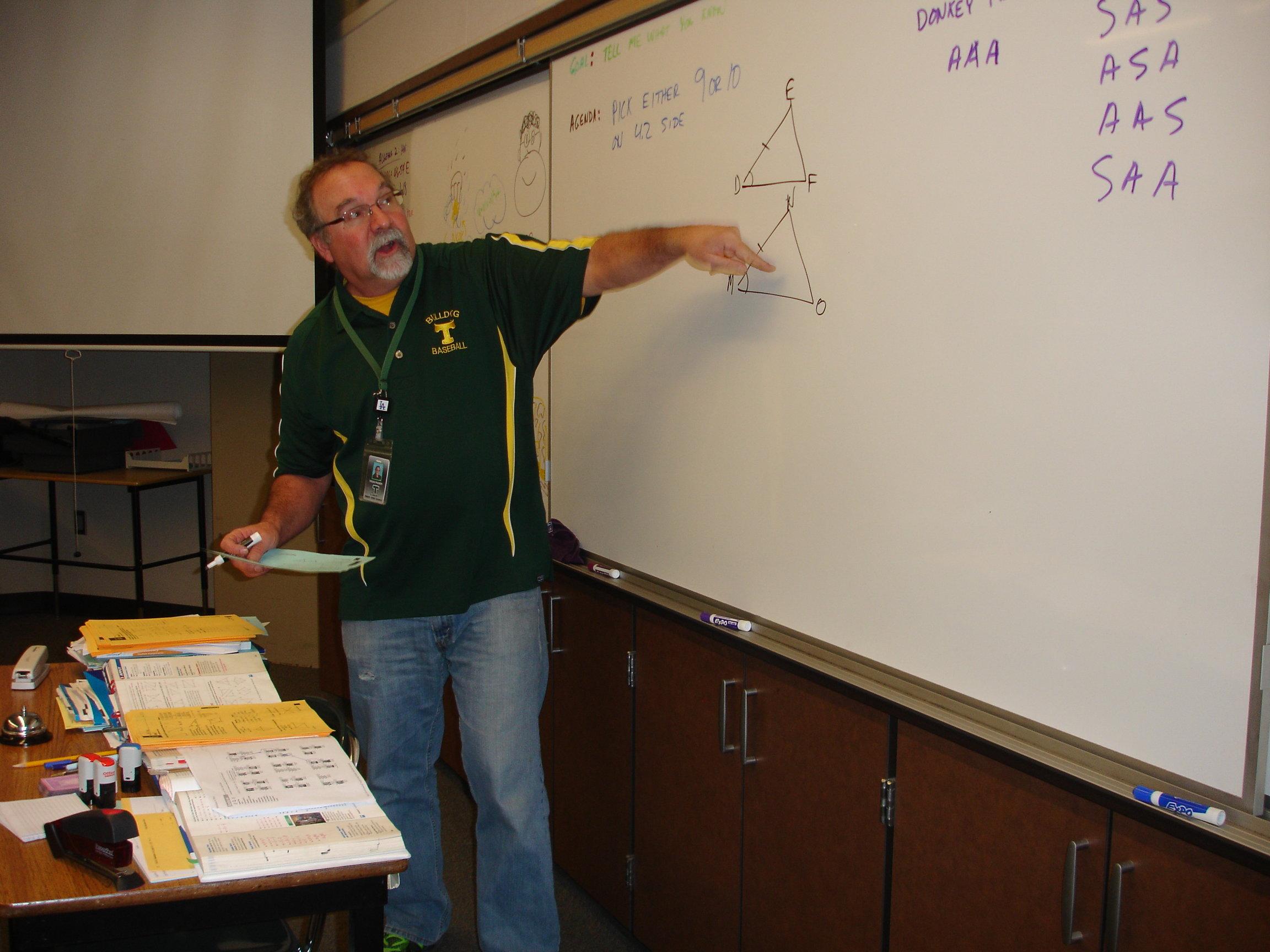 Math+teacher+Doug+Piuser+demonstrates+a+problem+on+the+board+for+his+class.