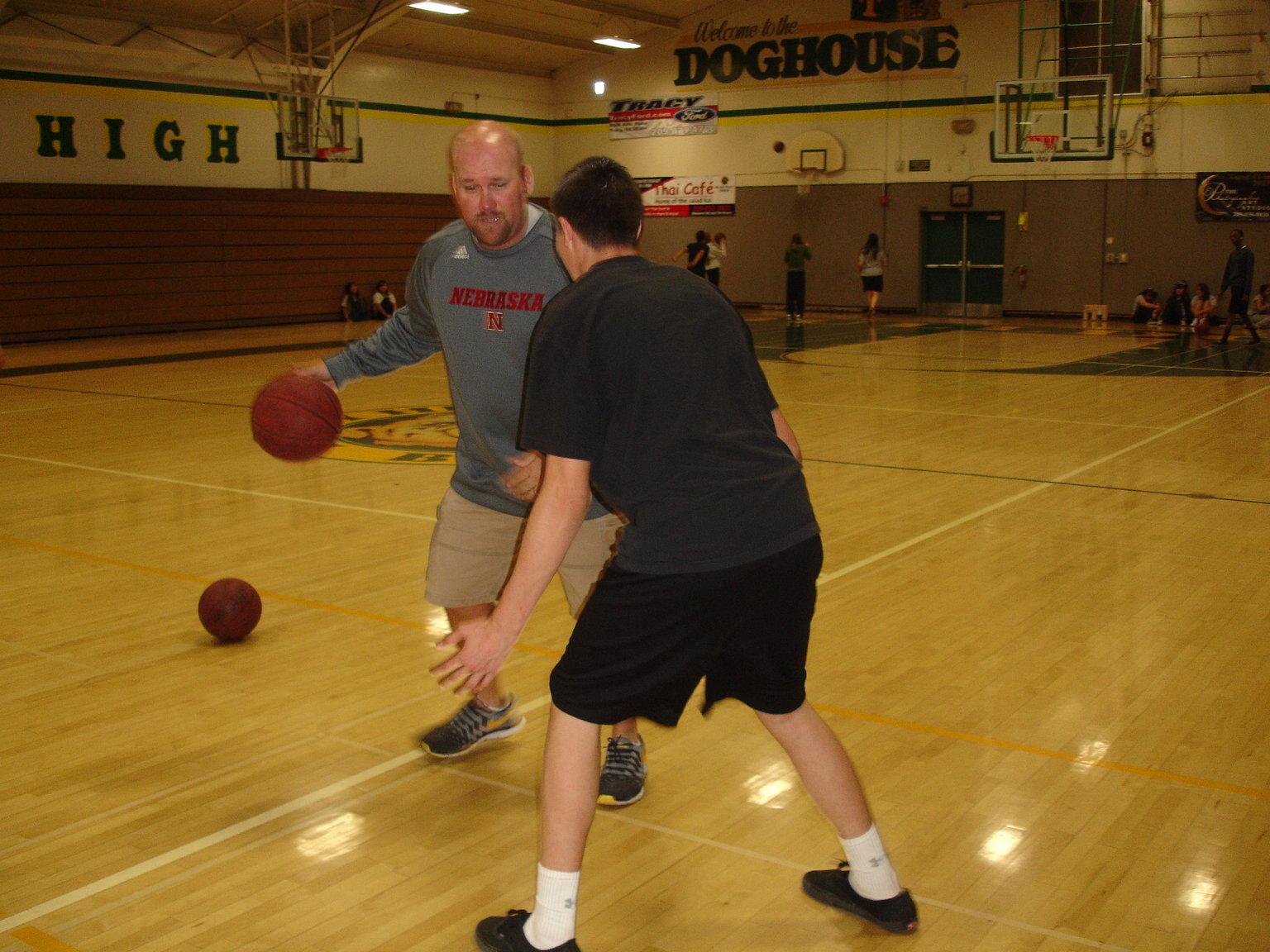 Physical Education teacher Matt Shrout challenging Logan Frigard in a basketball game.