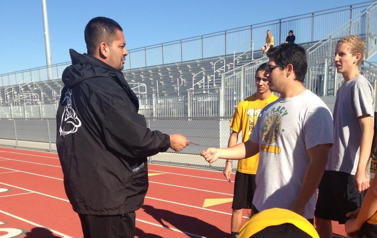 Physical Education teacher Derek Solano handing out running sticks to his sixth period class.
