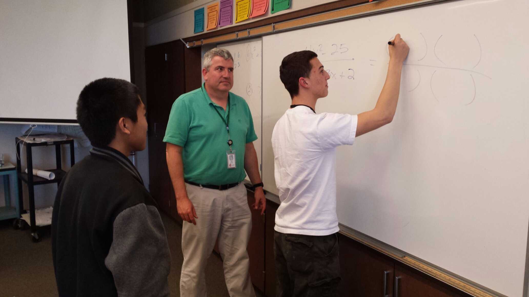 Math teacher David Daily assists a student with a math problem.