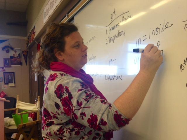 Mrs. Rockey is writting on the white board while teaching her class.