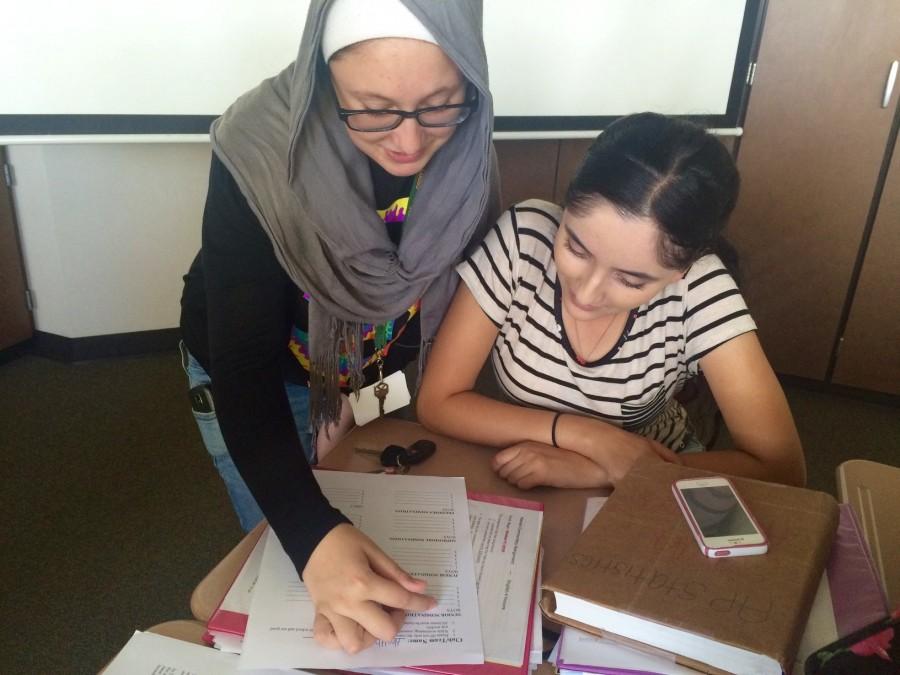 Health club president Fatima Mohammadi helps senior Sarah Anwar with nomination worksheet.