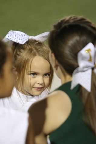 Cheer clinic student looks up to varsity cheerleader before performance at halftime show of varsity game, on Sept. 25.