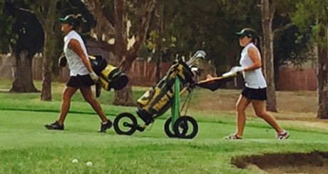 Two Tracy High golfers walk to the green.