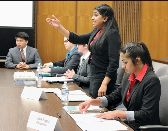 Captain, Angeli Indran, stands to make an argument as mock trial participant, Mehek Nagpal, takes notes during a practice tournament. 